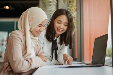 Muslim woman and asian business woman working together. couple woman working in office.