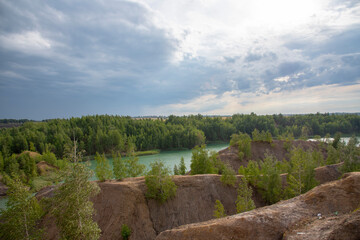 Fototapeta premium Green lake among sandy hills under a cloudy sky.