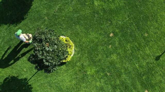 Male Landscaper Using Leaf Blower To Clean Freshly Trimmed Grass Lawn. Aerial View Of Lawn And Garden Maintenance In Routine Summer Upkeep. 