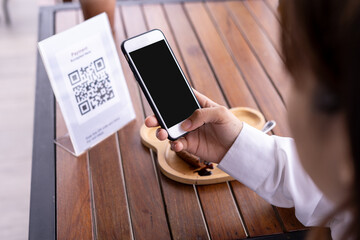 Close up of a woman's hand using a smartphone to scan a QR code to pay for food and drinks. Concept of scanning a QR code, using a mobile phone.