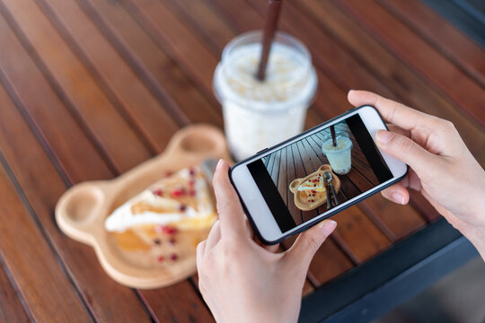 Women are using smartphones to focus on taking pictures of snacks and water in a coffee shop. Women take photo for social media updates or restaurant reviews.