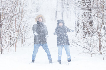 Fototapeta na wymiar Love, relationship, season and friendship concept - man and woman having fun and playing with snow in winter forest