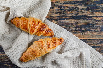 Fototapeta na wymiar Croissant on wooden and kitchen towel background, flat lay.