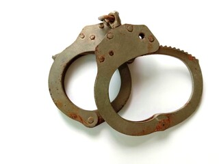 Rusty police handcuffs with shadow isolated on white background closeup. 