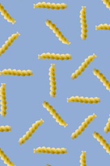 Obraz premium Fusilli pasta random flat lay on blue background without shadow. can be used as raw pasta background, poster, banner not pattern.