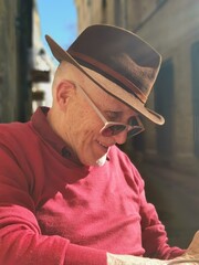 Un homme âgé portant un chapeau et assis dans un bistrot.