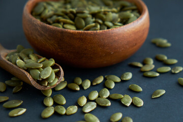 pumpkin seeds in a wooden bowl and vintage scoop. Close up on a black background. copy space for text