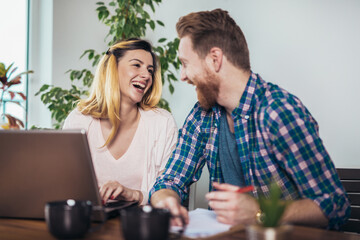 Young couple embracing and paying household bills or taxes on laptop online at home