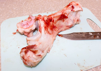 Raw pork bone on a chopping Board with a knife.