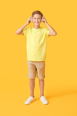 Little boy listening to music on color background