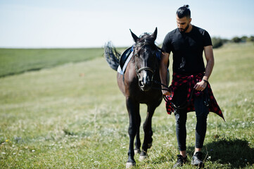 Arab tall beard man wear in black with arabian horse.