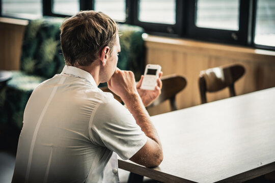 Young serious male doctor think about use bio rezonans therapy as alternative medicine, holding looking on small portable life balance bioresonance device for treatment thread worm invasions