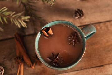 Cup of hot cocoa or hot chocolate on knitted background with fir tree and snow effect, traditional beverage for winter time