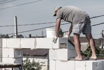 A worker builds the walls of a house from aerated concrete bricks.