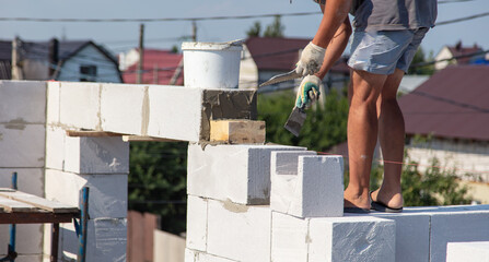 A worker builds the walls of a house from aerated concrete bricks.