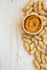 Jar full of peanut butter on a white wooden background, top view. Flat lay, overhead, from above. Space for text.