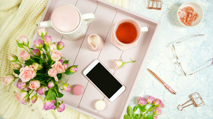 Blush pink theme cosy hygge desktop workspace with keyboard smart phone tea and rose on a stylish white marble textured background. Top view blog hero header creative flat lay. Negative copy space.