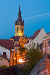 Fototapeta na wymiar View of Sibiu streets on background with tower of cathedral in night lights, Romania