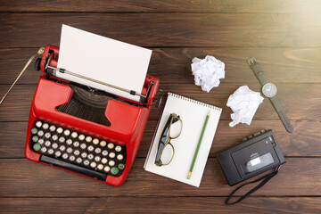 Writer or journalist workplace - vintage red typewriter, cassette recorder and notepad on the wooden desk