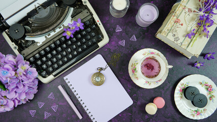 Purple theme vintage writers desktop workspace with typewriter, lavendar tea, hibiscus flowers and...
