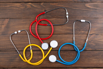 Workplace of a doctor. Colorful Stethoscopes on wooden desk background - Healthcare concept