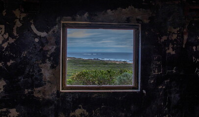 Seascape viewed through and framed by the window in an old and ruined building on a hill above the shore image in landscape format