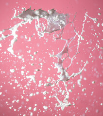 Splashing milk on a pink background.