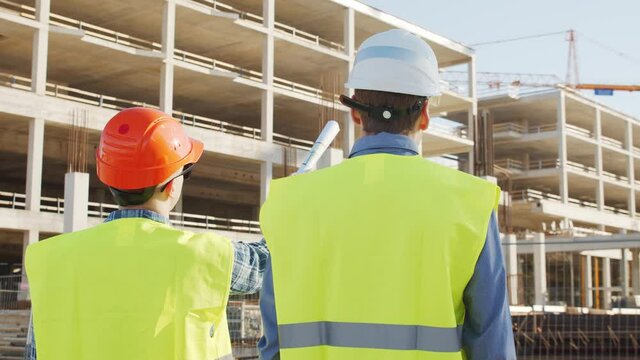 Professional builders standing in front of construction site. Office building and crane background.