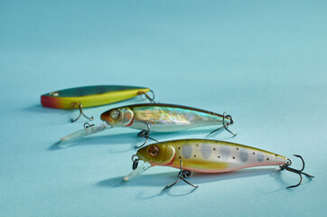 Fishing equipment. Three multi-colored plastic fishing wobblers on a blue background