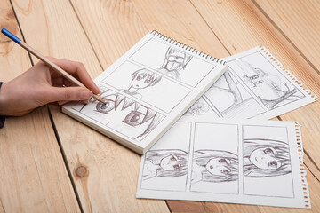 Artist drawing an anime comic book in a studio.