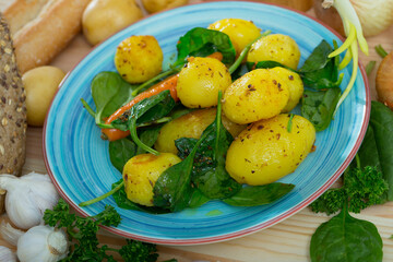 Scene with appetizing roasted new potatoes with spinach and greens