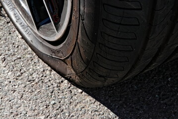 Close up of a punctured flat tire on the asphalt.