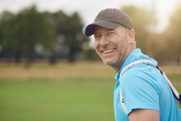 Smiling friendly middle-aged golfer turning to look back over his shoulder at the camera on the...