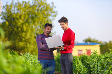 young agronomist analyzing field with farmer, indian farming