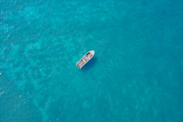 Aerial view of a white large boat on turquoise transparent water in the sun. Lonely boat on the water.