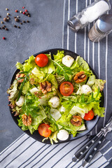 Vegetable salad with tomatoes, cheese, arugula and walnuts. Healthy and diet food concept. Top view