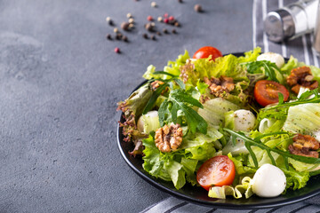 Vegetable salad with tomatoes, cheese, arugula and walnuts. Healthy and diet food concept. Text space