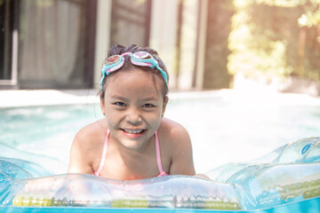 .happy little girl playing with inflatable ring in outdoor swimming pool on hot summer day. kids learn to swim. child water toys. children play in tropical resort. family beach vacation.