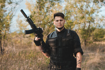 Young soldier in black uniform with an assault rifle.