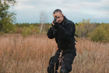 Special force soldier in black uniform aiming an assault rifle. Copy space