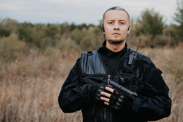 Portrait of special forces soldier in black uniform with a pistol. Copy space.