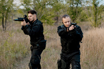 Fototapeta premium Two special forces soldiers in black uniform aiming in different directions.