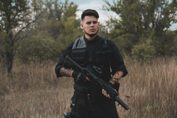 Fototapeta premium Young soldier in black uniform with an assault rifle.