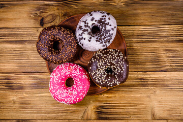 Plate with glazed donuts on a wooden table. Top view