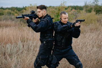 Fototapeta premium Two special forces soldiers in black uniform aiming in different directions.