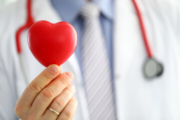 Male medicine doctor hands holding and covering red toy heart