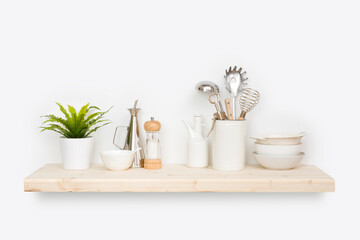 Fototapeta na wymiar Kitchen utensils, flower pot and dishware on natural wooden shelf