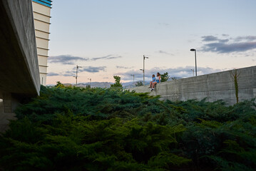 Two young women sitting in a city. They are meeting on a summer afternoon.