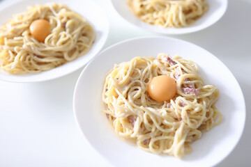On table are three plates of spaghetti carbonara with poached yolks. Traditional Italian food concept