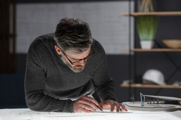 Architect drawing blueprints in office. Engineer sketching a construction project. Architectural plan. Close-up portrait of handsome bearded man concentrated on work. Business construction concept.